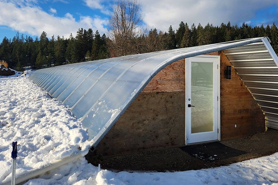 2023-25-greenhouse-in-the-snow-canada Geothermal greenhouse in winter conditions, maintaining warm interior despite snow-covered exterior in Armstrong, BC