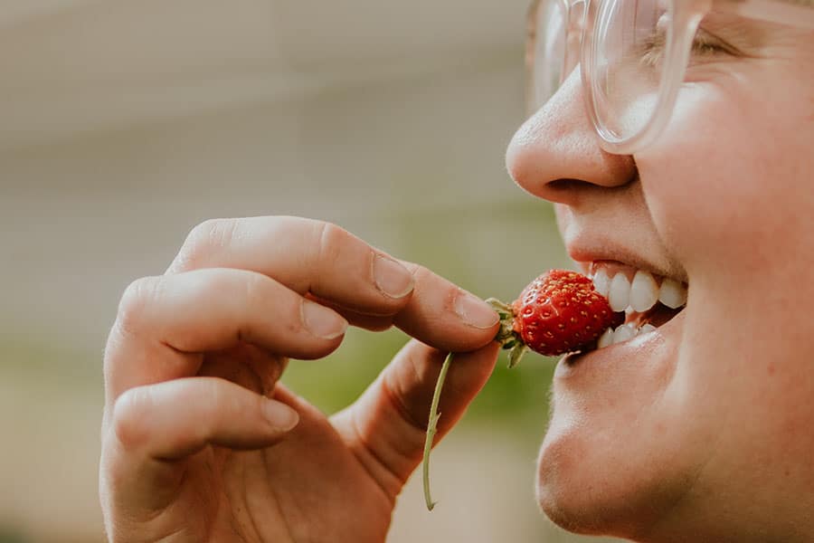 2023-37-greenhouse-in-the-snow-canada Woman enjoying fresh-picked strawberry grown inside a geothermal greenhouse in British Columbia